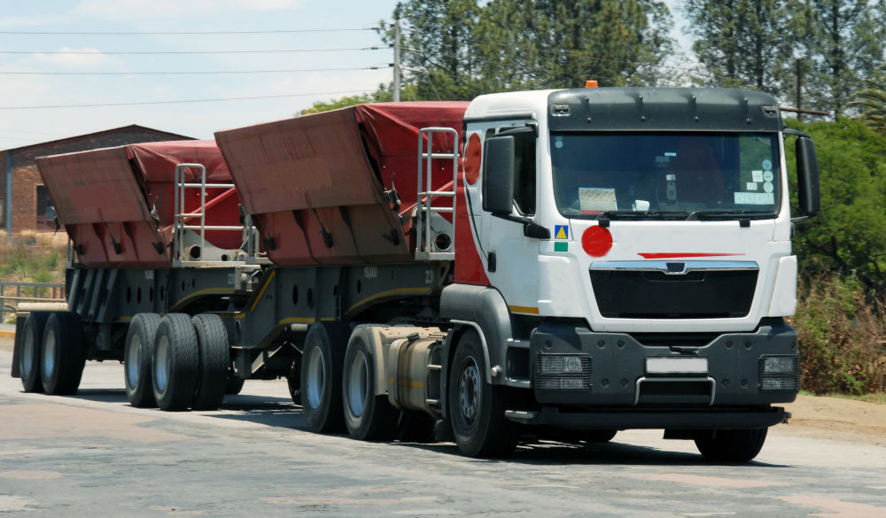 Truck Carrying Two Red Industrial Skips